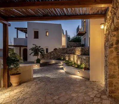a courtyard with a stone wall and a building with lights at The Authentic Village Boutique Hotel in Khóra Sfakíon