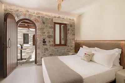 a bedroom with a bed with a stone wall at The Authentic Village Boutique Hotel in Khóra Sfakíon