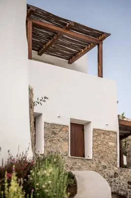 a white house with a wooden door and a stone wall at The Authentic Village Boutique Hotel in Khóra Sfakíon