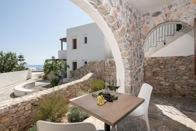 a table and chairs on a patio with a stone wall at The Authentic Village Boutique Hotel in Khóra Sfakíon