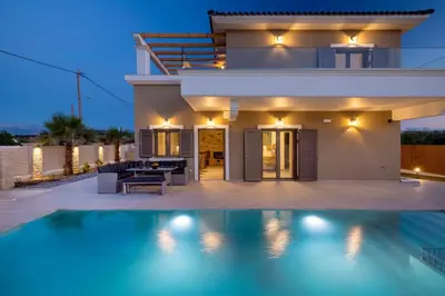 a villa with a swimming pool in front of a house at Villa Persephone in Tavronitis