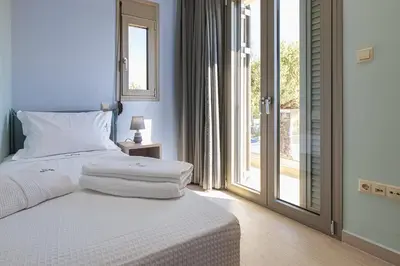 a bedroom with a bed with white sheets and a window at Cypress Village - Lux villa 5' from beach in Daratso