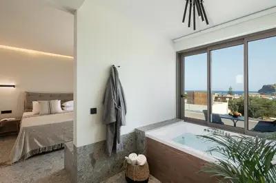a bathroom with a tub and a bed and a window at Casa Nostos in Agia Marina Nea Kydonias