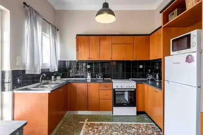 a kitchen with wooden cabinets and a white refrigerator at EMMANUEL’S COZY HOUSE in Chania Town