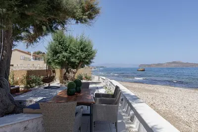 a table and chairs with a view of the water at Villa Seashell -Wonderful newly renovated villa on the beach in Galatás
