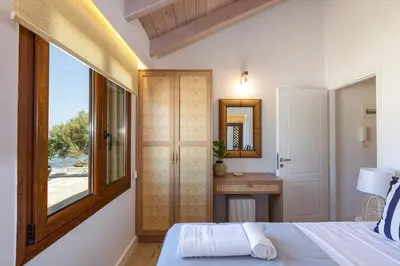 a bedroom with a bed and a window and a mirror at Villa Seashell -Wonderful newly renovated villa on the beach in Galatás