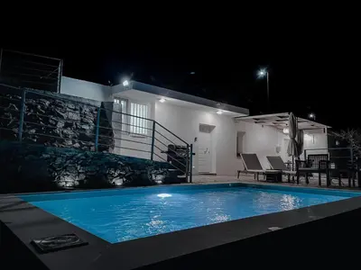 a swimming pool in front of a house at night at Kampos View - Quiet House at the end of the Road, private pool in Kámbos