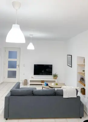 a living room with a blue couch and a tv at Kampos View - Quiet House at the end of the Road, private pool in Kámbos