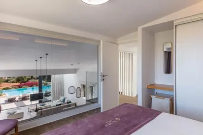 a bedroom with a large window with a view of a living room at Chic Dream Villa in Agios Onoufrios