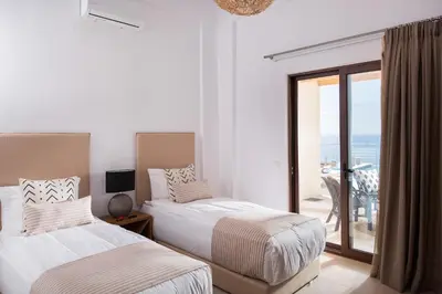 two beds in a bedroom with a view of the ocean at Villa Thetis Sfakia in Sfakiá