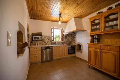 a large kitchen with wooden cabinets and stainless steel appliances at Villa Tzitzifes in Tzitzifés