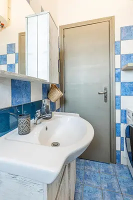 a bathroom with a white sink and blue tiles at kissamos seaside bliss in Kissamos