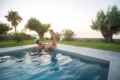 a man and a woman standing in a swimming pool at Isalos Seafront Villa I Sea fragrance in Chania Town