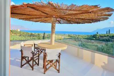 a table and chairs on a balcony with an umbrella at Anemomili Villas in Drapaniás