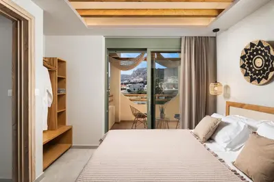 a bedroom with a large bed and a balcony at Villas Plumeria in Palaiochóra