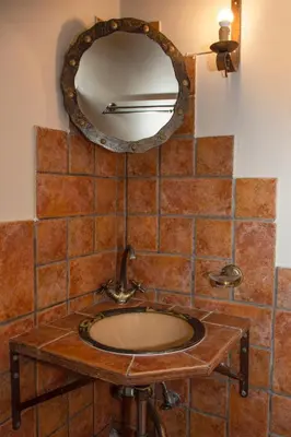 a bathroom sink with a mirror on a tiled wall at STAMATOGIANNIS Traditional Apartments in Kalivianí