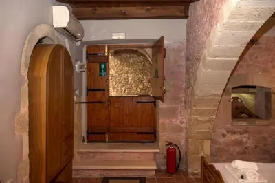 a bathroom with a wooden door and a stone wall at STAMATOGIANNIS Traditional Apartments in Kalivianí