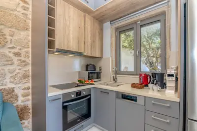 a kitchen with white cabinets and a stone wall at Villa Maritini in Chania Town
