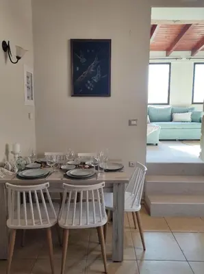 a dining room with a wooden table and white chairs at Villa Anthemida Chania in Ayiá
