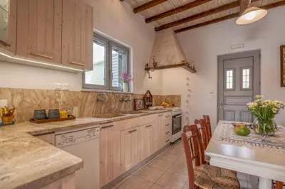 a kitchen with wooden cabinets and a table with chairs at Lahardi - Seaside House in Kissamos