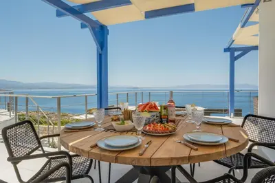 a wooden table with food on top of a balcony at Villa Hemera ocean view private heated pool in Chorafakia