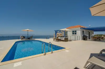 a swimming pool on a patio with the ocean in the background at Villa Hemera ocean view private heated pool in Chorafakia