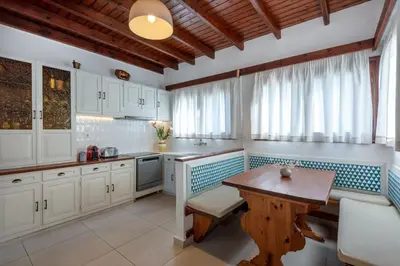 a kitchen with white cabinets and a wooden table at SeaView villa with piano by Chania Living Stories in Chania Town