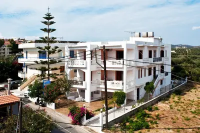 a white house with balconies and a tree at Captain Michalis Apartments - 750m from Kalamaki Beach in Galatás
