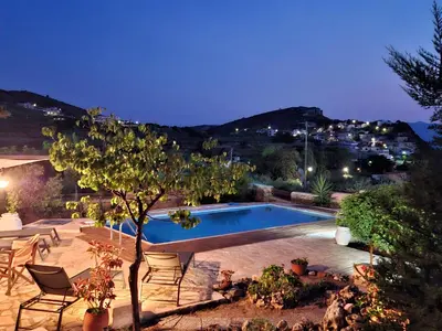 a swimming pool in a yard with chairs and a tree at Villa Terpsi in Ravdhoúkha