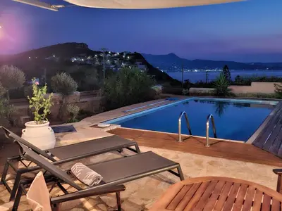 a swimming pool with a table and a chair next to it at Villa Terpsi in Ravdhoúkha