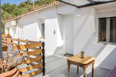 a white house with a wooden table on a balcony at Casa Elafonisi N2-10min from the beach in Plokamianá