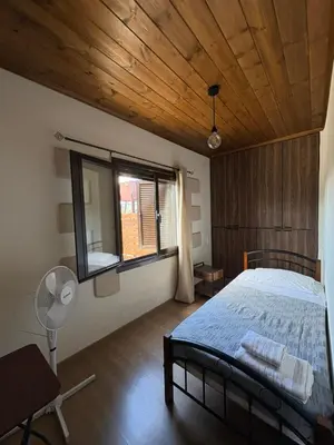 a bedroom with a bed with a wooden ceiling and a window at Nikos Traditional House in Maláthiros