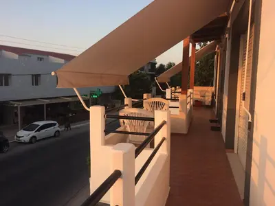 a balcony with awning and a car on a street at Ouranos Studios in Kalamaki Chanion