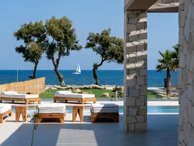 a patio with a view of the ocean and a sailboat at Artemis Villa, Beachfront Retreat with Heated Pool, By ThinkVilla in Tavronitis