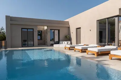a swimming pool with lounge chairs and a house at Amalthia Villa, Heated Pool & Walk to the Beach, By ThinkVilla in Tavronitis