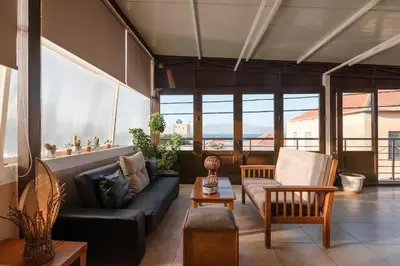 a living room with a couch and chairs and windows at Calliope Rooms in Kissamos
