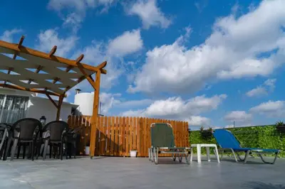 a patio with chairs and a wooden fence at Calliope Rooms in Kissamos