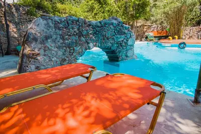 a pool with a bench next to a rock in the water at Malaxiana Houses in Maláxa