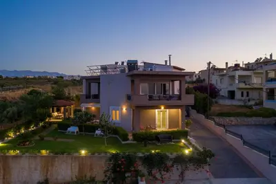 a villa with a view of a house at dusk at Tholos Apartments in Chania Town