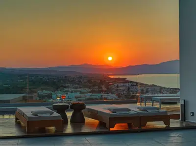 a view of a sunset from a balcony with a table at Alectrona Living Crete, Apartment RocSea in Plataniás