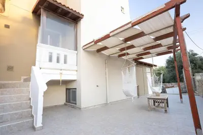 a patio with a wooden pergola next to a building at Sofia's seaview house in Plataniás