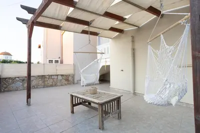 a porch with a hammock and a table and a swing at Sofia's seaview house in Plataniás