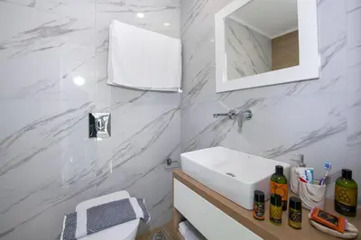 a white bathroom with a sink and a mirror at Deluxe City Hotel in Chania Town