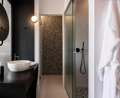 a bathroom with a sink and a glass shower door at Nuovo Luxury Suites in Daratso
