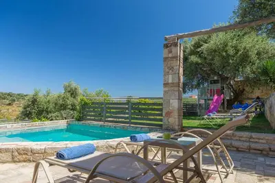 a swimming pool with a table and chairs next to it at Margarita's Villas in Chania Town