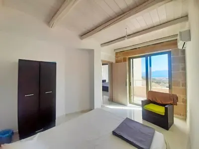 a bedroom with a bed and a chair and a window at Mitato Stylianos in Kounoupítsa