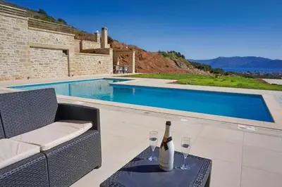 a bottle of wine sitting on a table next to a swimming pool at Mitato Stylianos in Kounoupítsa