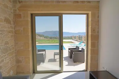 a house with a glass door leading to a patio at Mitato Stylianos in Kounoupítsa