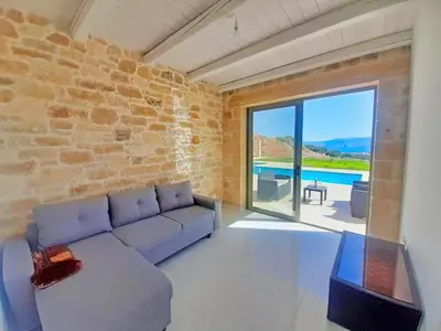 a living room with a couch and a pool at Bangalows Stylianos in Kounoupítsa