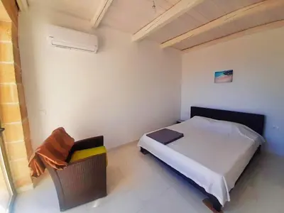 a bedroom with a bed and a chair in it at Bangalows Stylianos in Kounoupítsa